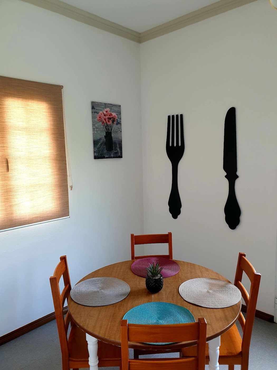 Dining room with wooden table, chairs, and colorful placemats